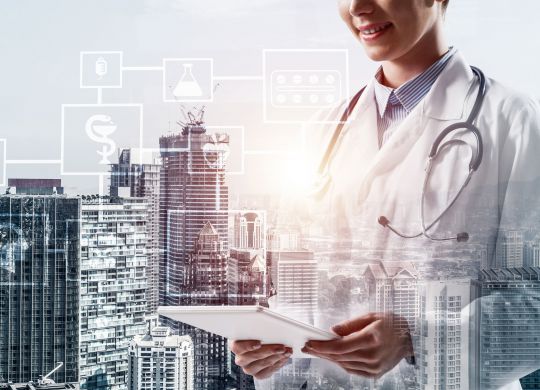 Cropped image of confident medical industry employee standing outdoors and holding tablet in hands. Young female doctor using tablet. Double exposure with medical interface icons